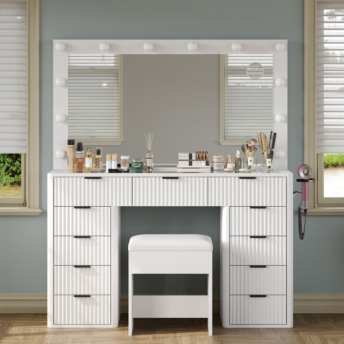 White fluted vanity desk with lighted mirror and matching stool in a bedroom